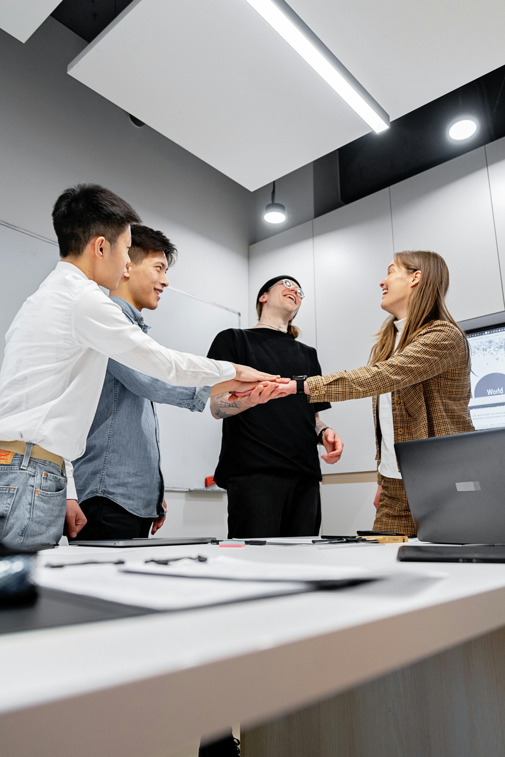 A diverse group of professionals building unity with a handshake in a modern office.